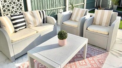 garden furniture with a sofa, two armchairs and coffee table on a pink outdoor geometric rug 