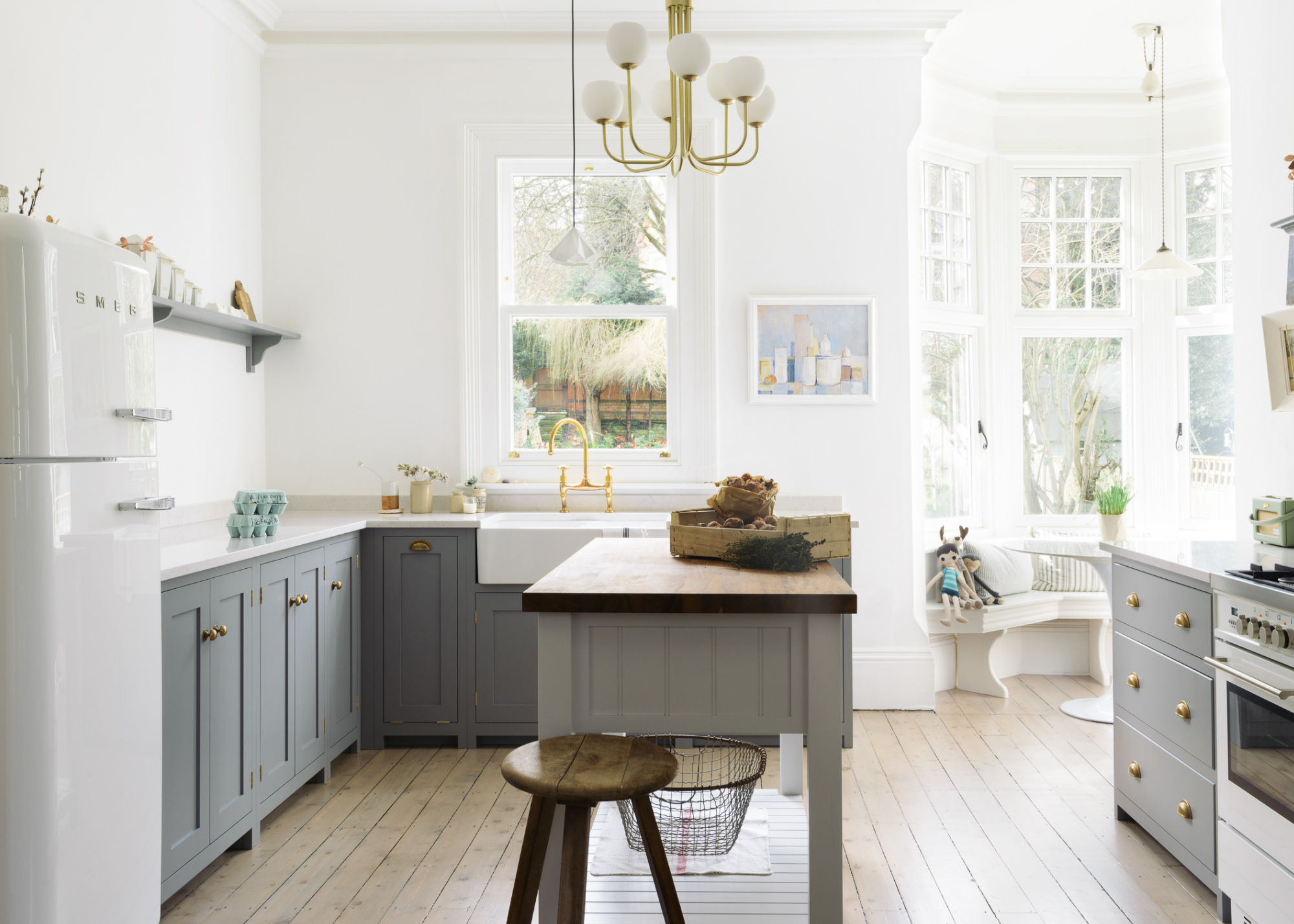 A butcher&#039;s countertop in the kitchen with gray cabinets as well as a kitchen island in the middle with a wooden bar stool beside it