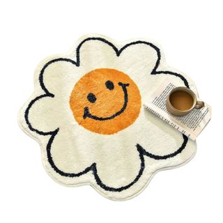 A daisy rug with a smiley face, and book and coffee on top