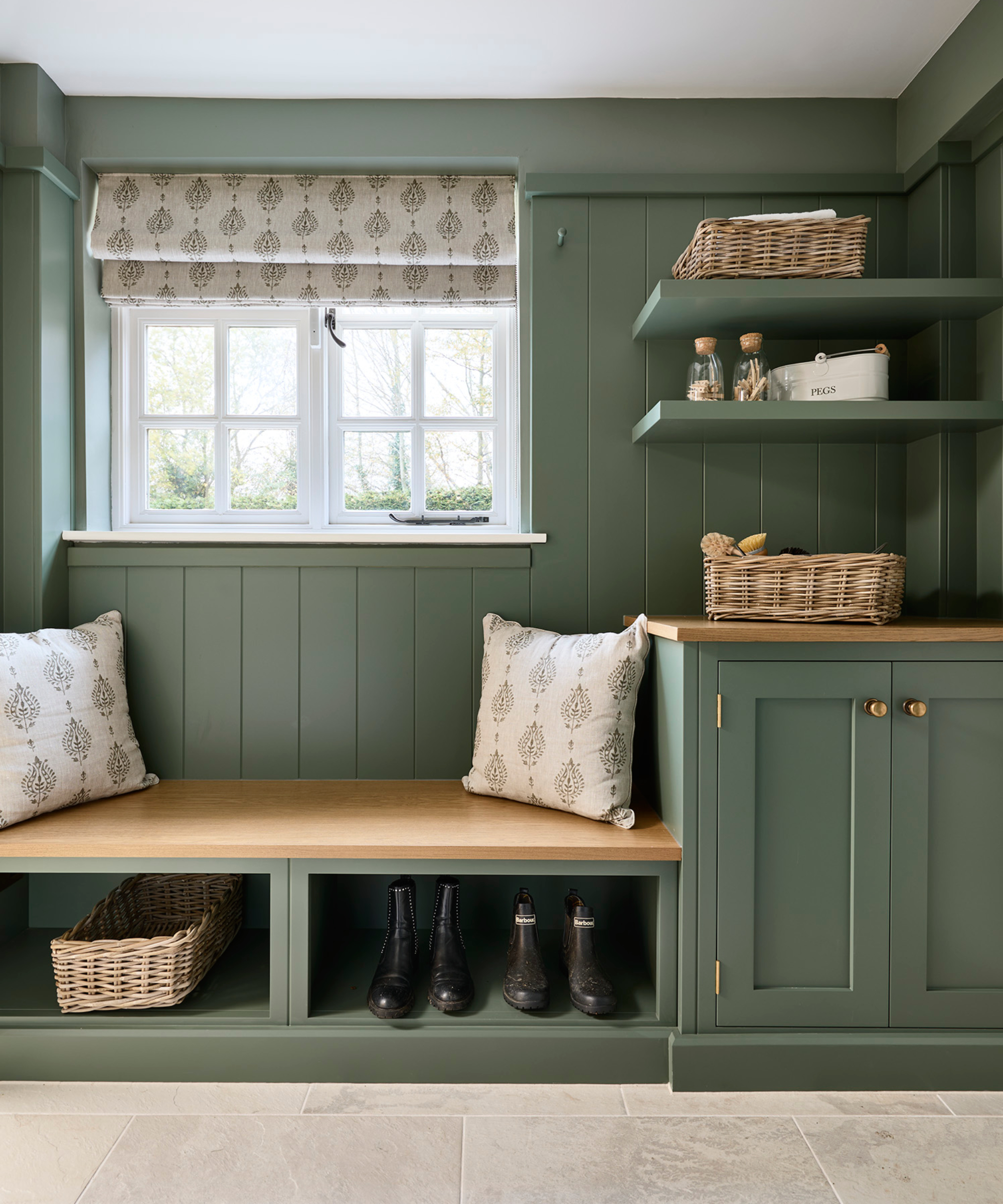 boot room area by window with green panelled wall, green cupboards and shelves, seating area with wooden top and shelving below for shoes