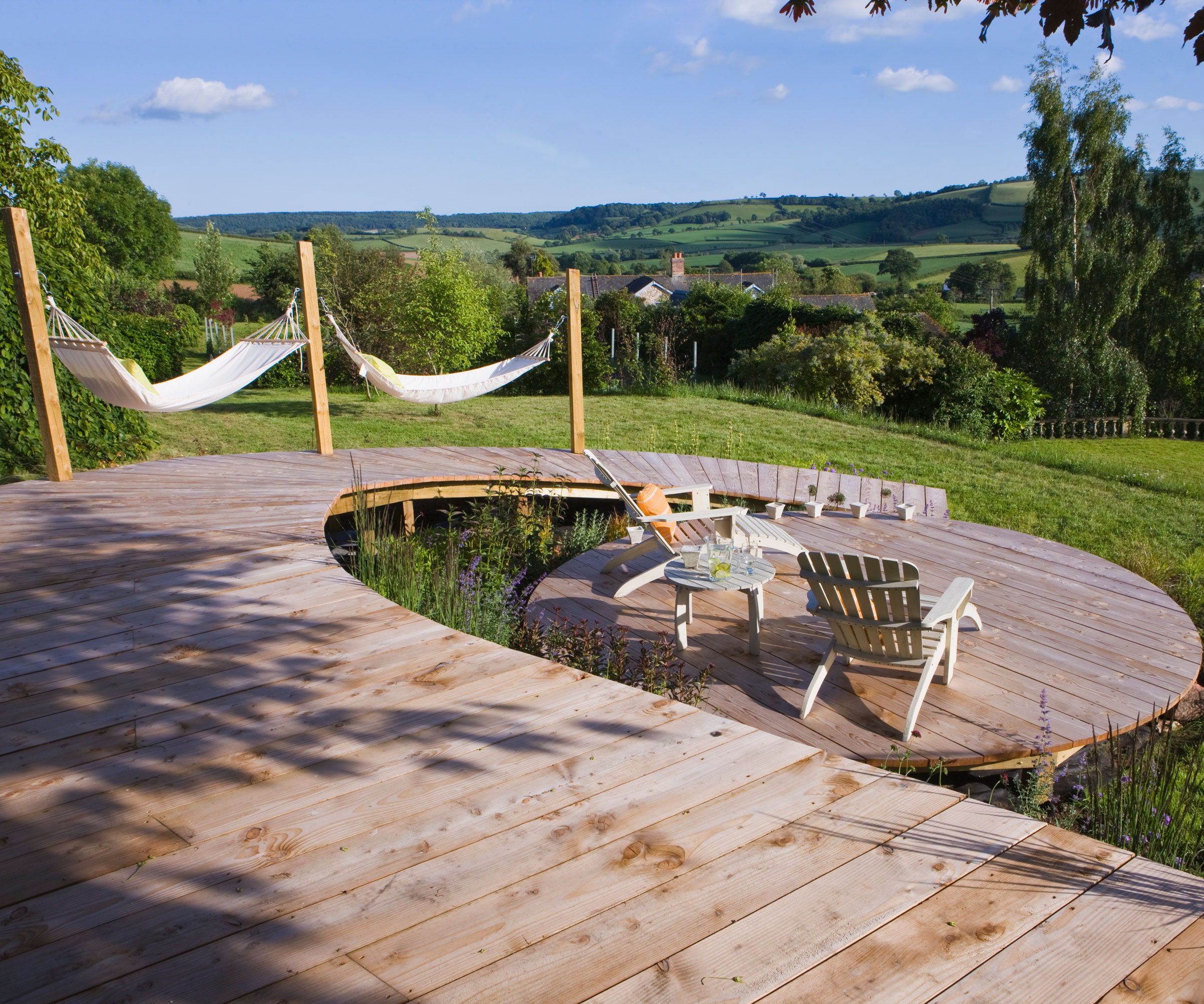 circular wooden deck with wooden pathway, hammocks and garden furniture, with views to countryside