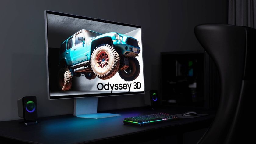 Official promo image of the Odyssey 3D gaming monitor on a desk facing a gaming chair on the right hand side of the image.