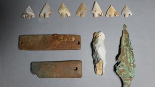 A collection of weapons, including flint arrowheads.