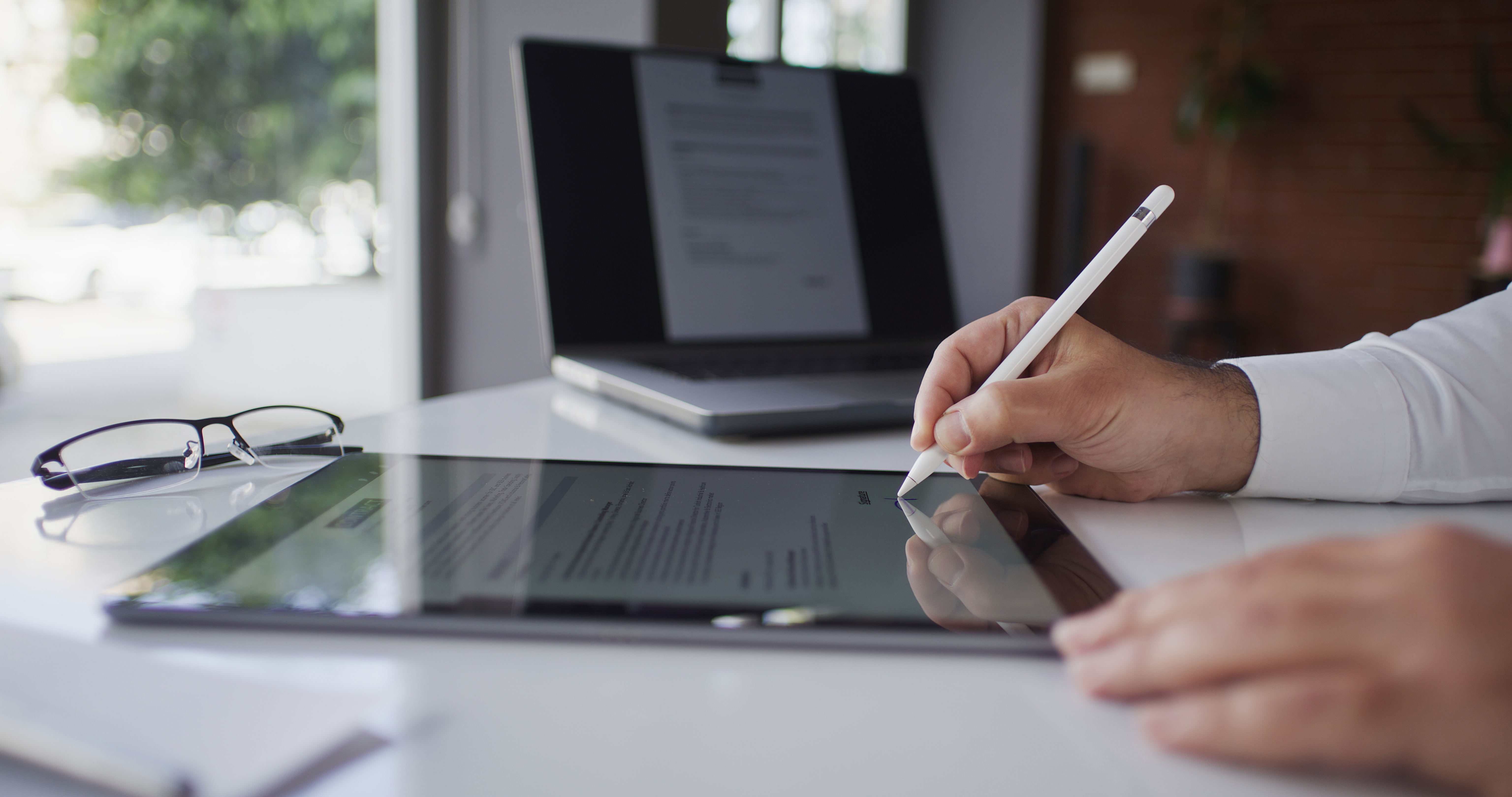 Digital document being signed on an iPad tablet with an Apple Pencil.