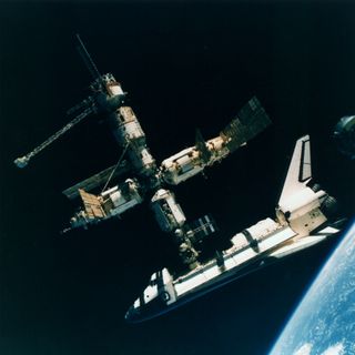 During NASA's STS-71 mission aboard the shuttle Atlantis, cosmonauts Anatoliy Y. Solovyev and Nikolai M. Budarin, Mir-19 commander and flight engineer, respectively, temporarily unparked their Soyuz spacecraft from the cluster of Mir elements to perform a brief flyaround and photograph the visiting shuttle in July 1995.