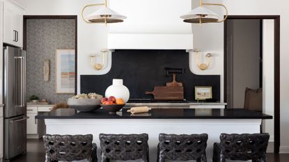 kitchen with white walls and white island with black worktop, and black woven stools