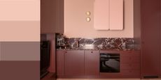 tonal kitchen color with burgundy cabinets, pale pink walls and range, two wall sconces, and burgundy marble backsplash and counter