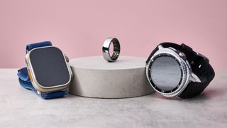 The Apple Watch Ultra 2 and Samsung Galaxy Watch 8 Classic sit either side of a stone podium, on which sits the Oura Ring 3.