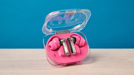 The Nothing Earbuds (3a) in pink, on a wooden surface