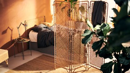a beige, light-filled bedroom with bed, rattan room divider and rattan headboard