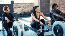 Group doing aerobic exercise on rowing machines in gym