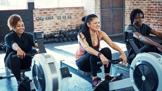 Group doing aerobic exercise on rowing machines in gym