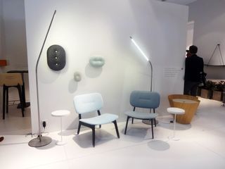 A sitting area with two chairs with black frames and cushions in shades of blue, two round coffee tables and two standing lamps with thin long globes.