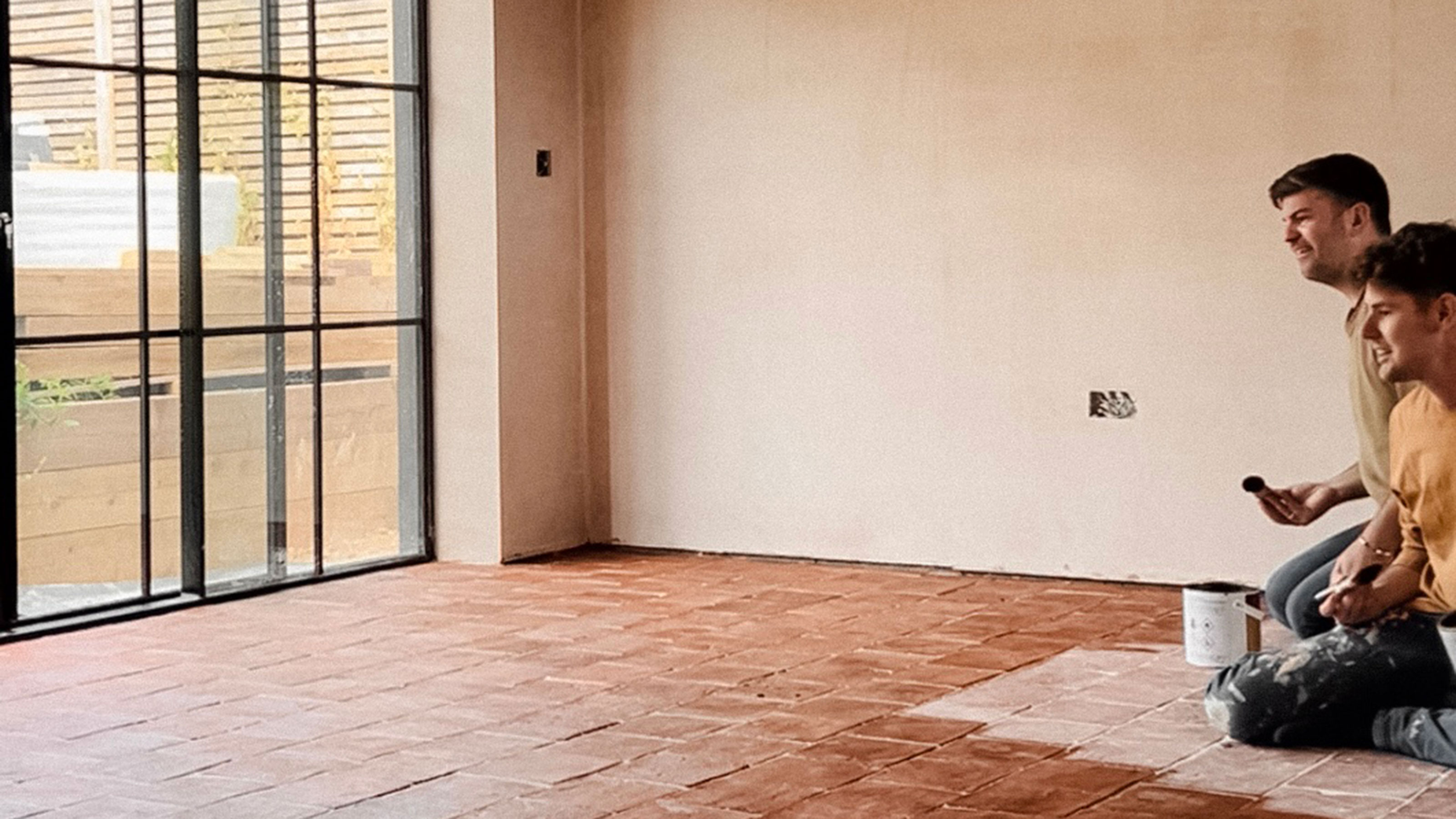 Two men kneeling in the midst of treating terracotta tiled floors