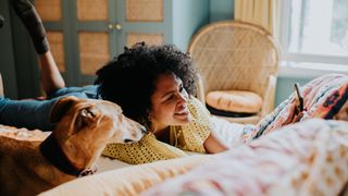 woman lying in bed with dog watching phone
