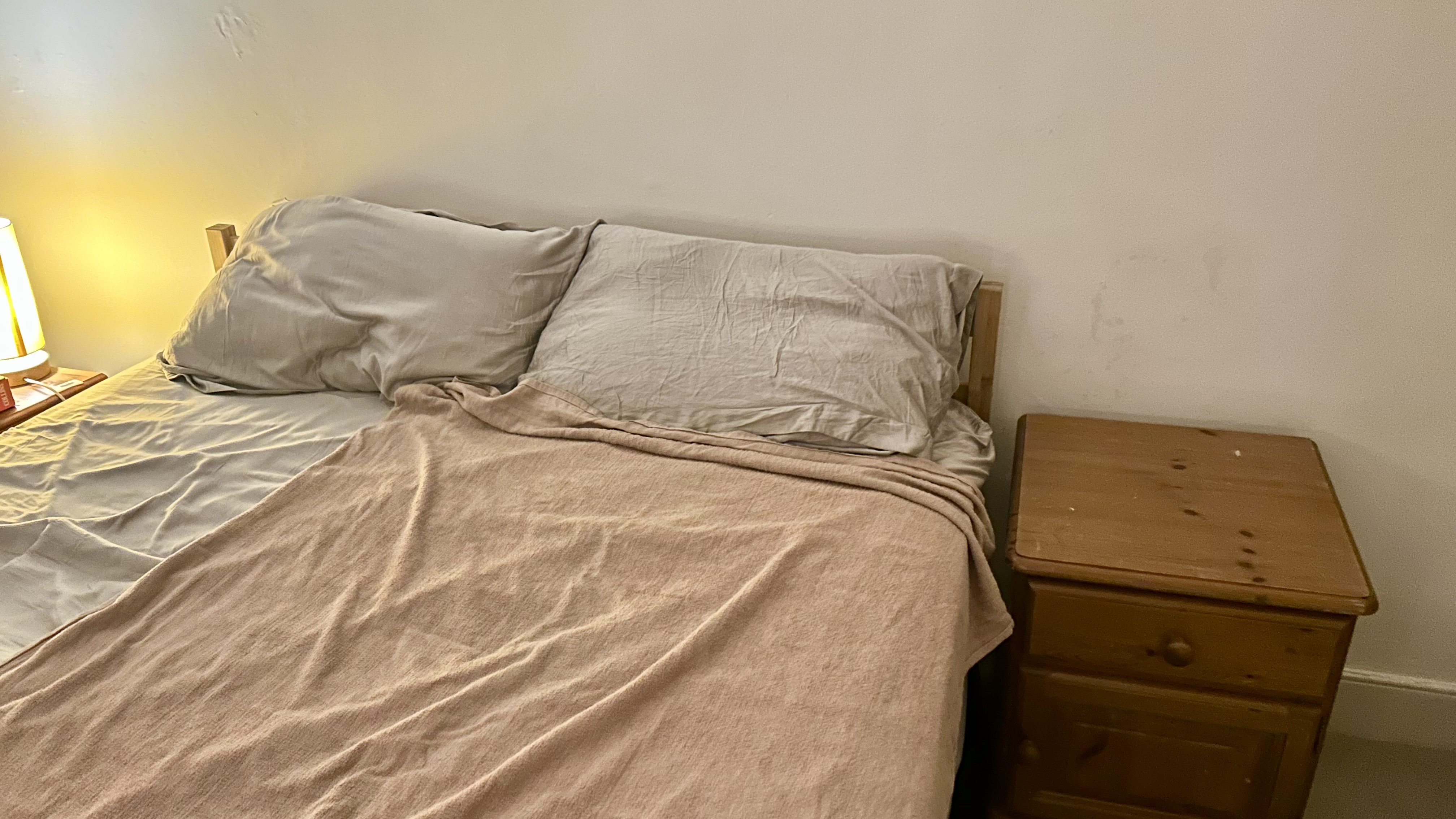 A pink towel lay flat on a bed with grey bedding