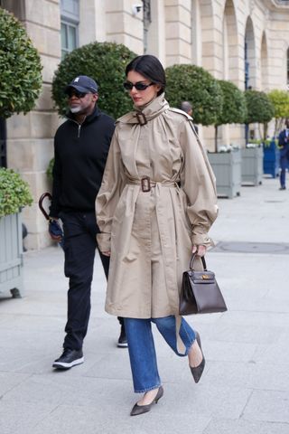 Kendall Jenner wears satin kitten heels in Paris with a funnel neck trench coat.