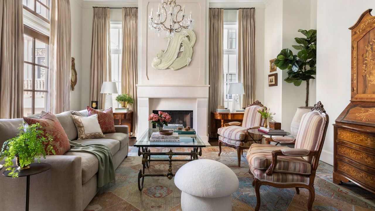 living room with cream walls taupe sofa and mushroom ottoman with striped armchairs pale stone fireplace and texture artwork