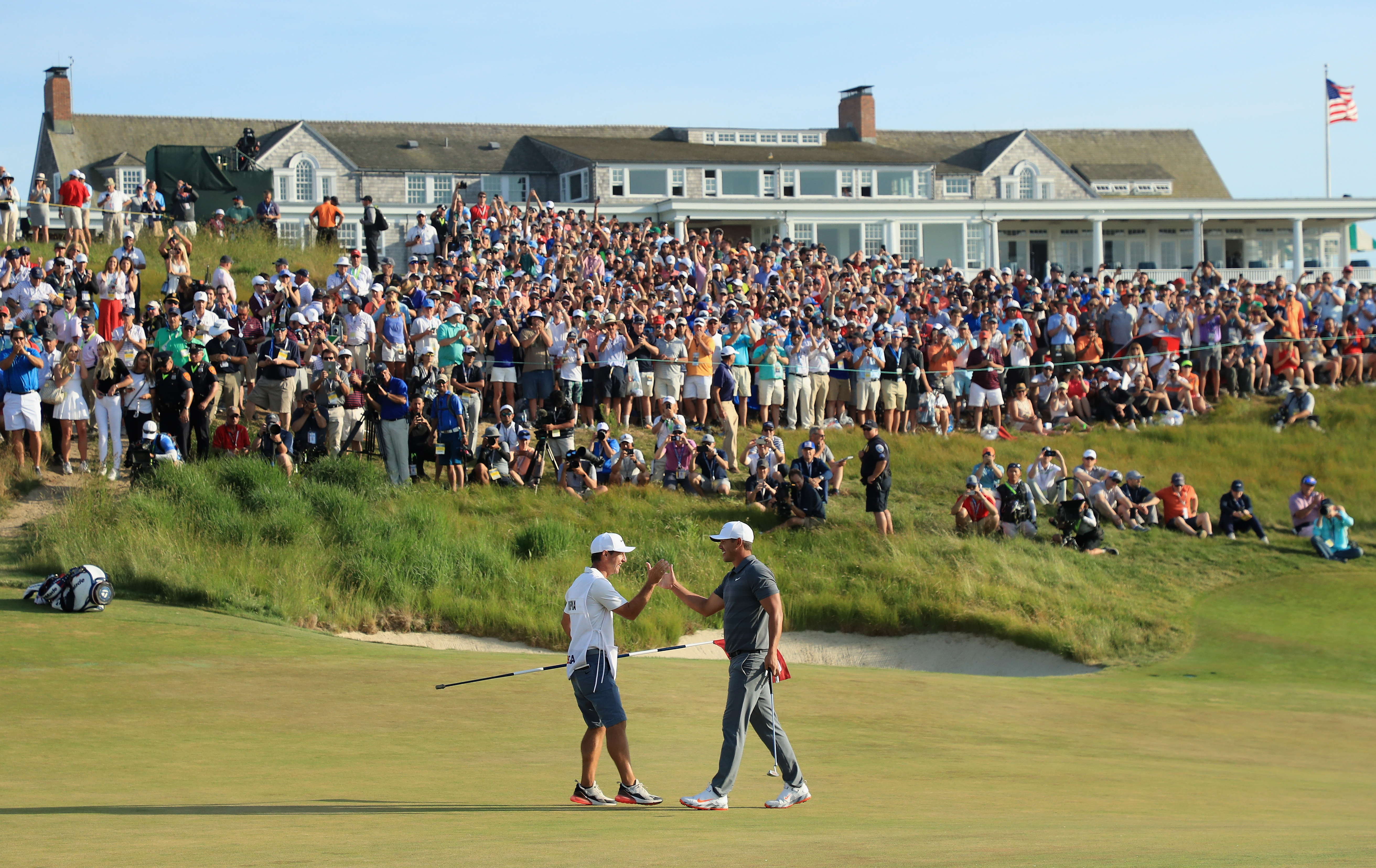 Brooks Koepka high fiving caddie on green at 2018 US Open held at Shinnecock Hills