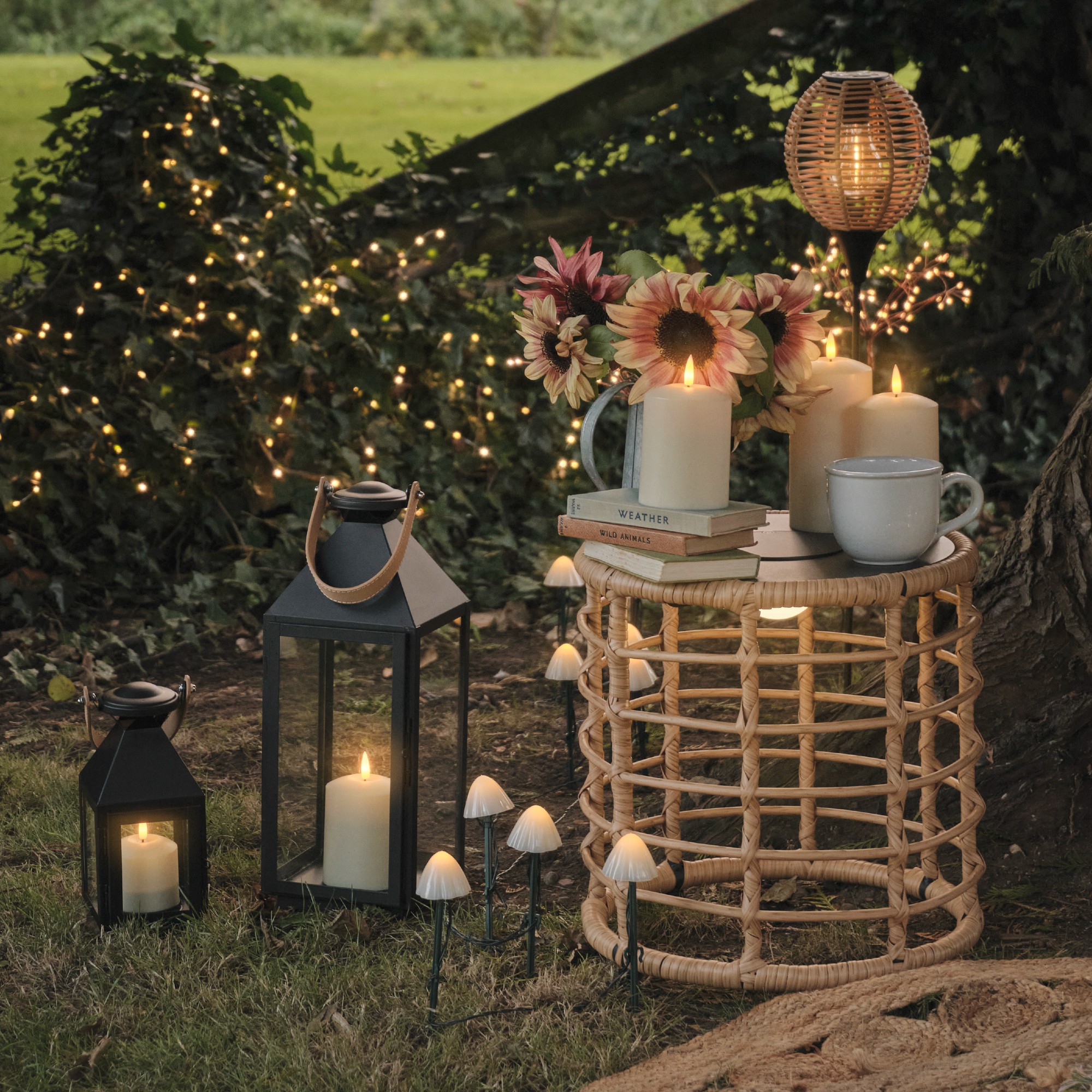 A garden with a rattan side table with a stack of books and a vase of flowers surrounded by mushroom stake lights from Lights4fun