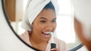 A woman brushing her teeth with an electric toothbrush