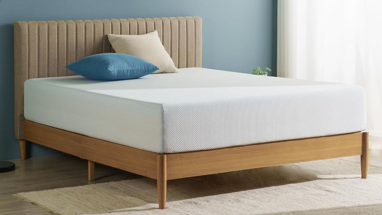 The Zinus Green Tea Memory Foam mattress on a wooden bed frame in a bedroom