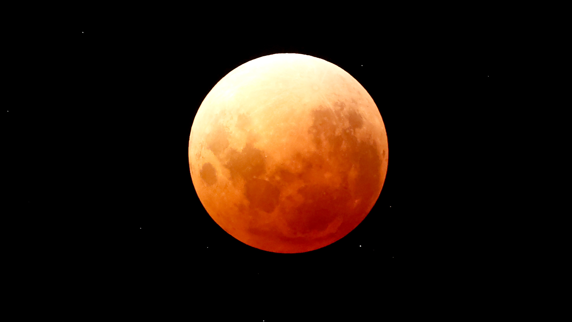 An organge-red full moon is pictured in a black sky during a total lunar eclipse.