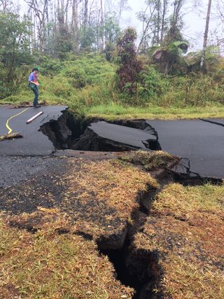 A geologist with the Hawaiian Volcano Observatory stands next to cracks on Nohea Street in Leilani Estates yesterday (May 17).