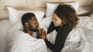 Woman looks at her partner who is snoring next to her in bed