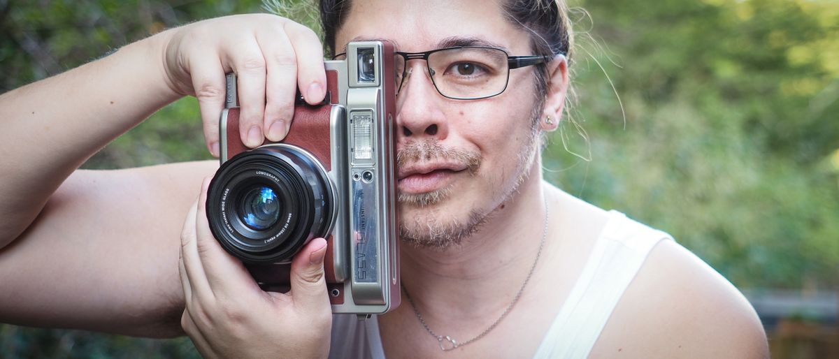 James Artaius holding a Lomo&#039;Instant Wide Glass camera, against a woodland background