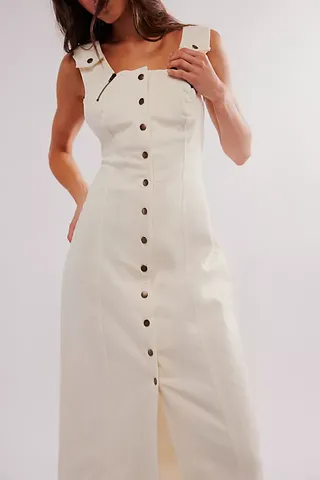 a model wears a sleeveless white dress with buttons down the front