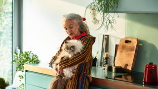 A senior woman holds her large ragdoll cat
