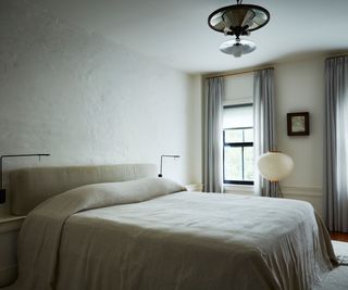 bedroom with beige walls and bed linen and two windows