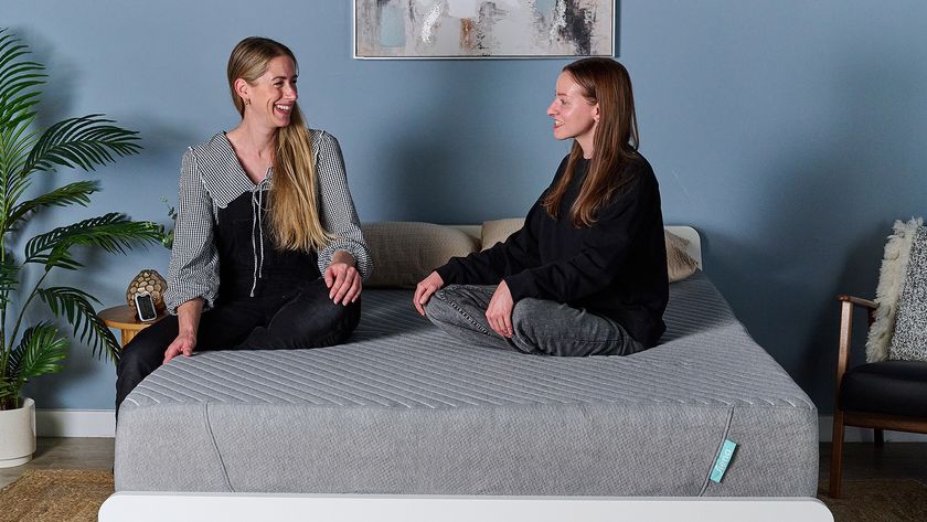 Two of our mattress testers sit on the Siena Signature Mattress on a bed frame in our testing studio. On the left, Nicola Appleton sits close to the side of the mattress to test the edge support. On the right, Frances Daniels sits on the sleeping area of the bed to better understand the comfort.