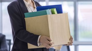 Employee holding box of belongings, depicting a layoff