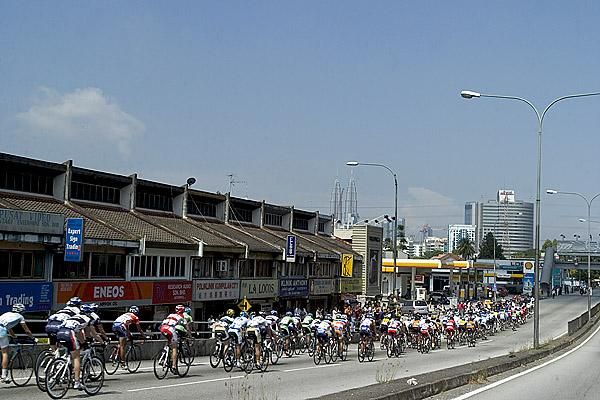 The peloton speed along a Kula Lumpur freeway with the KL Twin Towers in the distance.