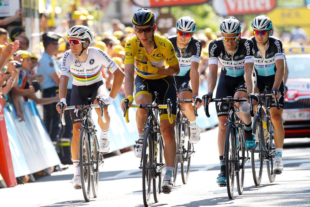 A battered Tony Martin crosses the finish line surrounded by teammates.