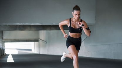 A woman running outdoors with her headphones in