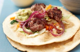 lamb meatballs in a wrap with red onion and salad
