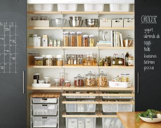 kitchen cupboard with blackboard paint doors and storage jars and storage trolleys full of dried food by elfa