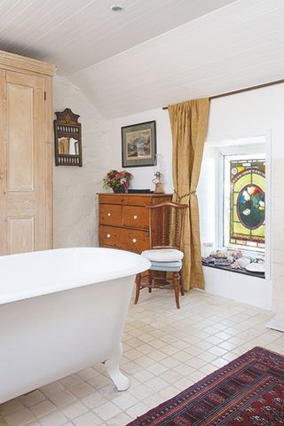 bathroom in a converted animal byre with stained glass window in a coastal home