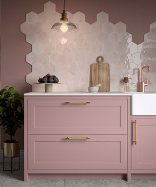 Pink modern kitchen with pink cabinets and walls, brass fittings, and hexagonal glazed backsplash idea in abstract formation.