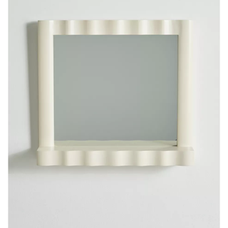 cream square wall mirror with a wavy border and shelf detail at the base