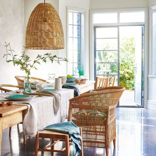 Dining room with mismatched chairs, linens and rattan lampshade