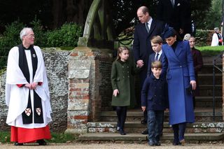 Revd Paul Williams (L) stands bay as Britain's Prince William, Prince of Wales (C) and Britain's Princess Charlotte of Wales (2L), Britain's Catherine, Princess of Wales (R) walks away from the church with Britain's Prince George of Wales and Britain's Prince Louis of Wales after attending the Royal Family's traditional Christmas Day service