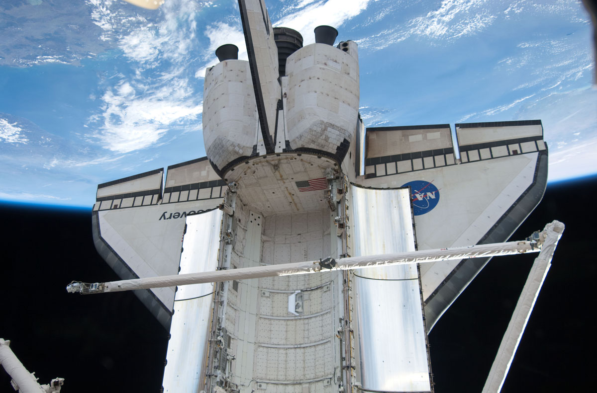 Backdropped by Earth&#039;s horizon and the blackness of space, space shuttle Discovery and its remote manipulator system/orbiter boom sensor system (RMS/OBSS) is featured in this image photographed by an STS-133 crew member while docked with the International