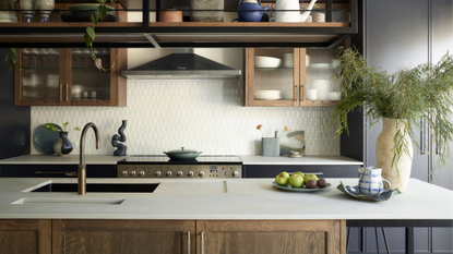 Modern kitche with wooden, glass fronted cabinetry, brass finishes and dark grey cabinets. 