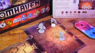 Gloomhaven figures, components, board pieces, booklet, and box on a wooden table