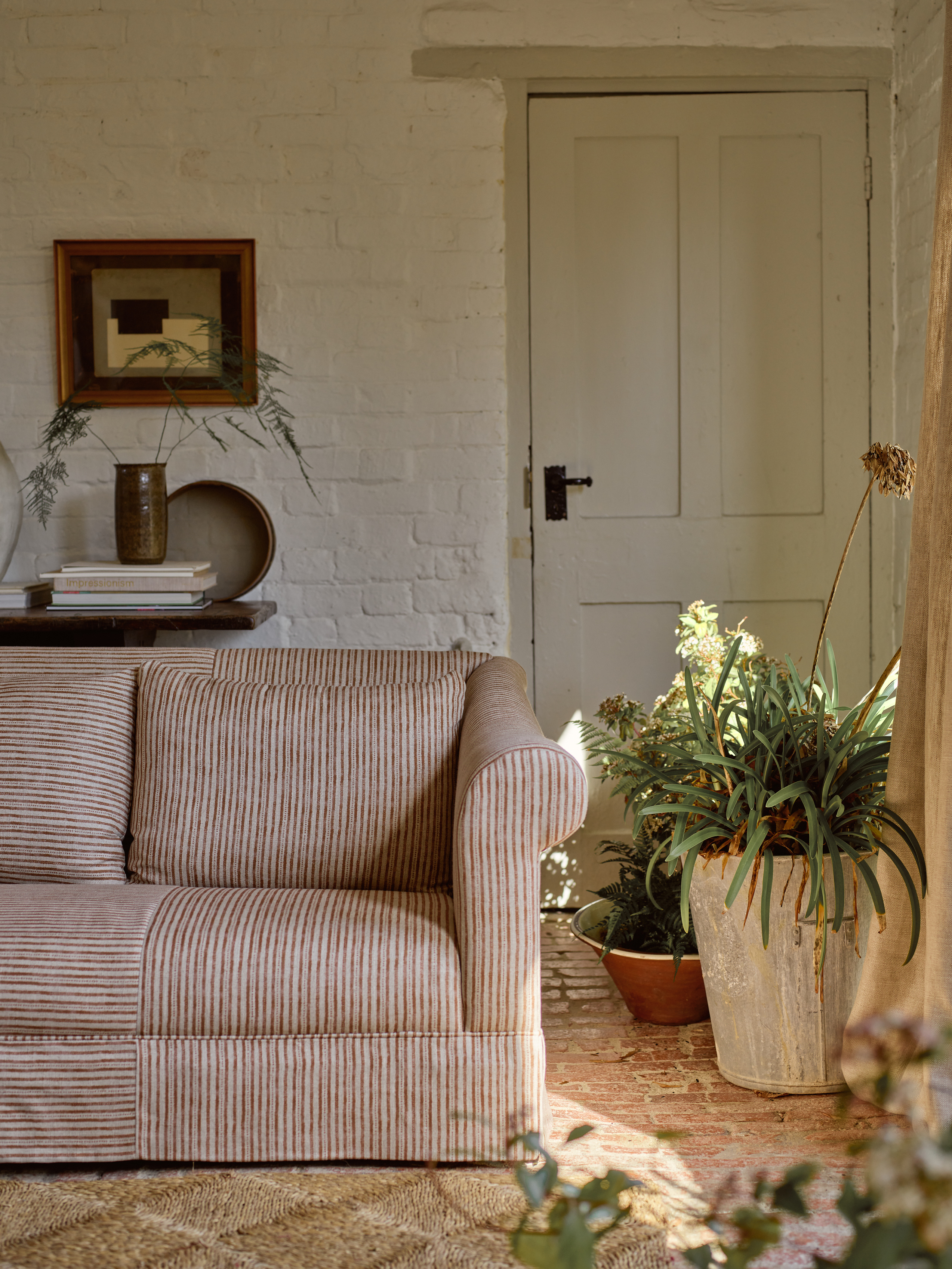a striped sofa in a country home with a painted brick wall