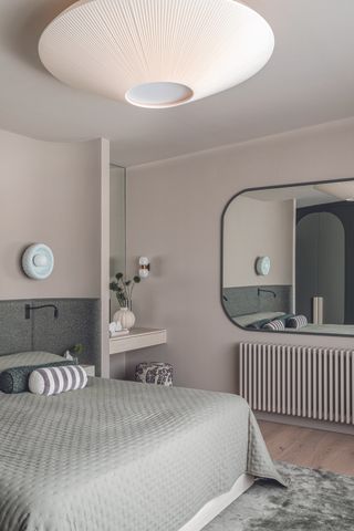 A bedroom with grey soft furnishings and headboard with an in-built vanity table